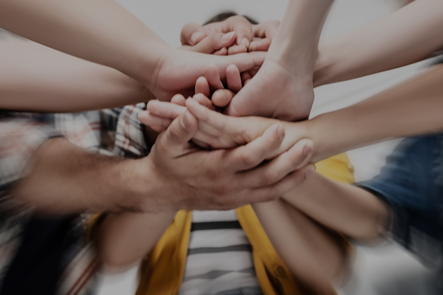 A group of U.S.-based respondents stacking hands together in a show of unity and teamwork, photographed from below.