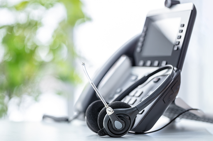 A modern VoIP desk phone with a headset on a blurred office background delivers real business value.