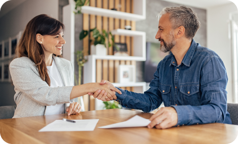 A man and woman shaking hands over a table in a modern office, smiling, with Uniphore paperwork in front of them.