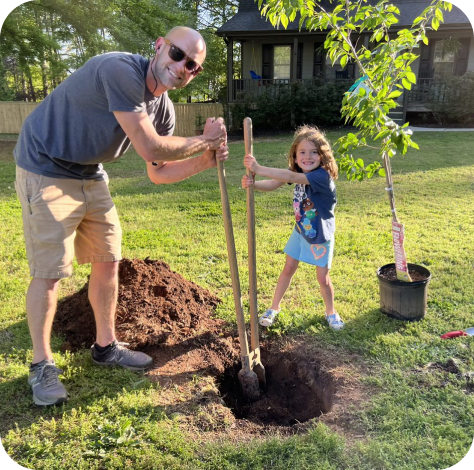 A man and a little girl plant a tree in honor of Earth Day 2022.