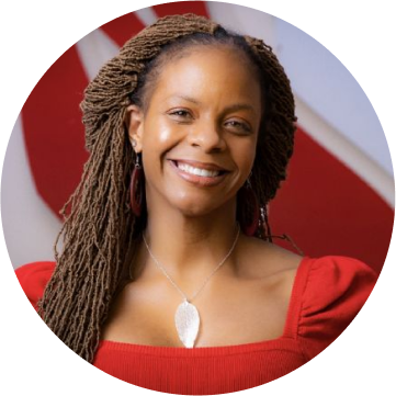 A woman with dreadlocks smiling in front of a red circle at a webinar.