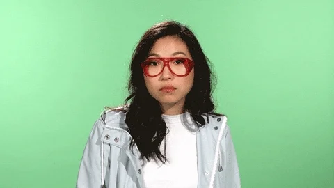 A woman with red glasses in front of a green screen engages.