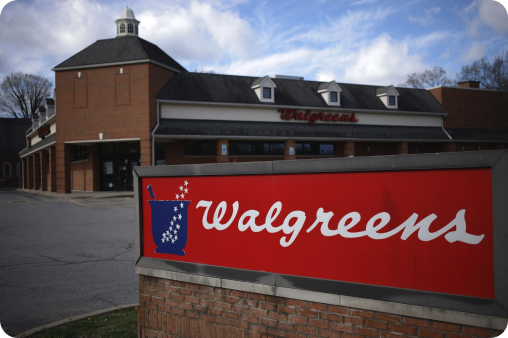 A Walgreens sign stands in front of a brick building.