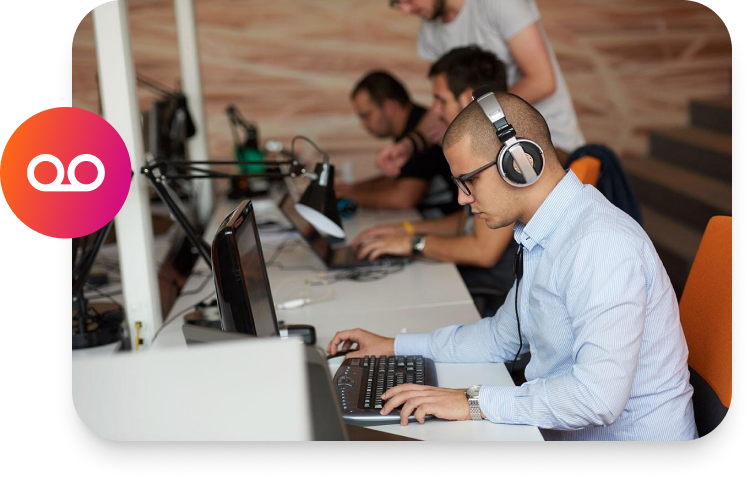 A man is working on a computer with headphones on for compliance recording.