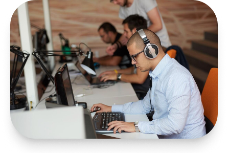 A man is working on a computer with headphones on, ensuring compliance recording.