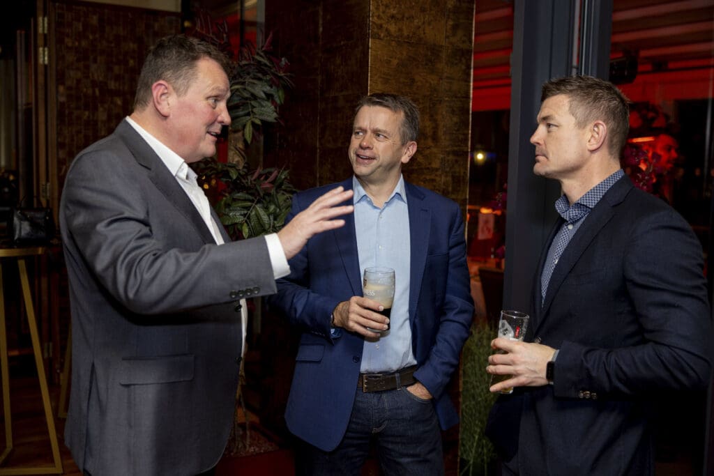 Three men engaged in conversation at an event captured in PR photos.